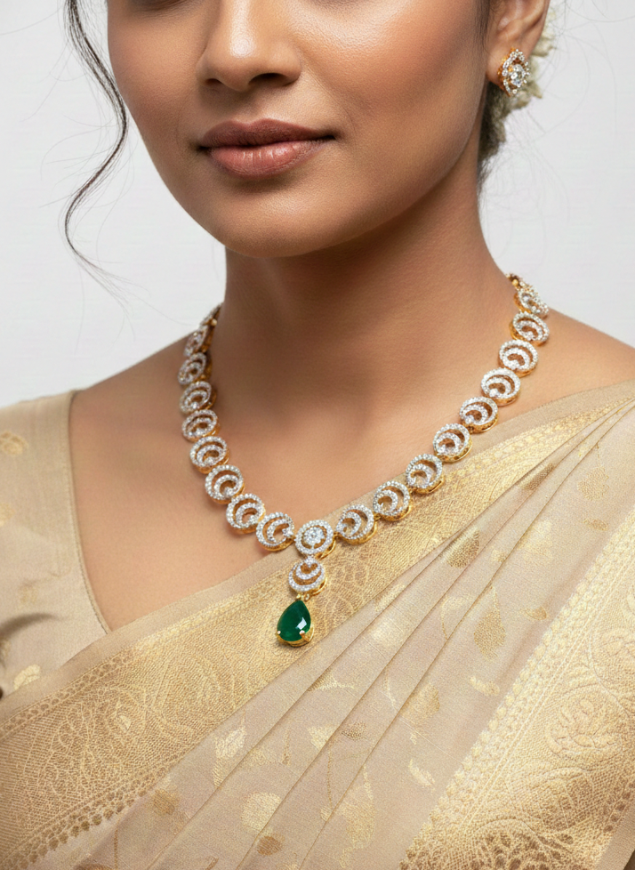 Woman wearing a gold saree with a diamond necklace featuring an emerald pendant.