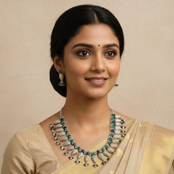 Woman wearing a traditional silver necklace and saree against a beige background